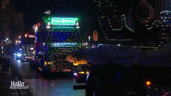 Ein Konvoi mit beleuchteten und dekorierten Lkws fährt durch die Dunkelheit. © Screenshot 