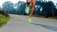 Läufer mit neongelben Sportschuhen trainiert auf asphaltiertem Weg © colourbox Foto: homydesign