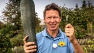 Peter Rasch hält zeigt zwei unterschiedlich große Zucchini hoch © NDR 